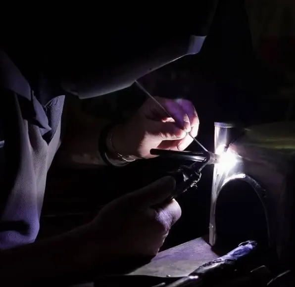 Saldatore al lavoro su un tubo metallico con la torcia TIG